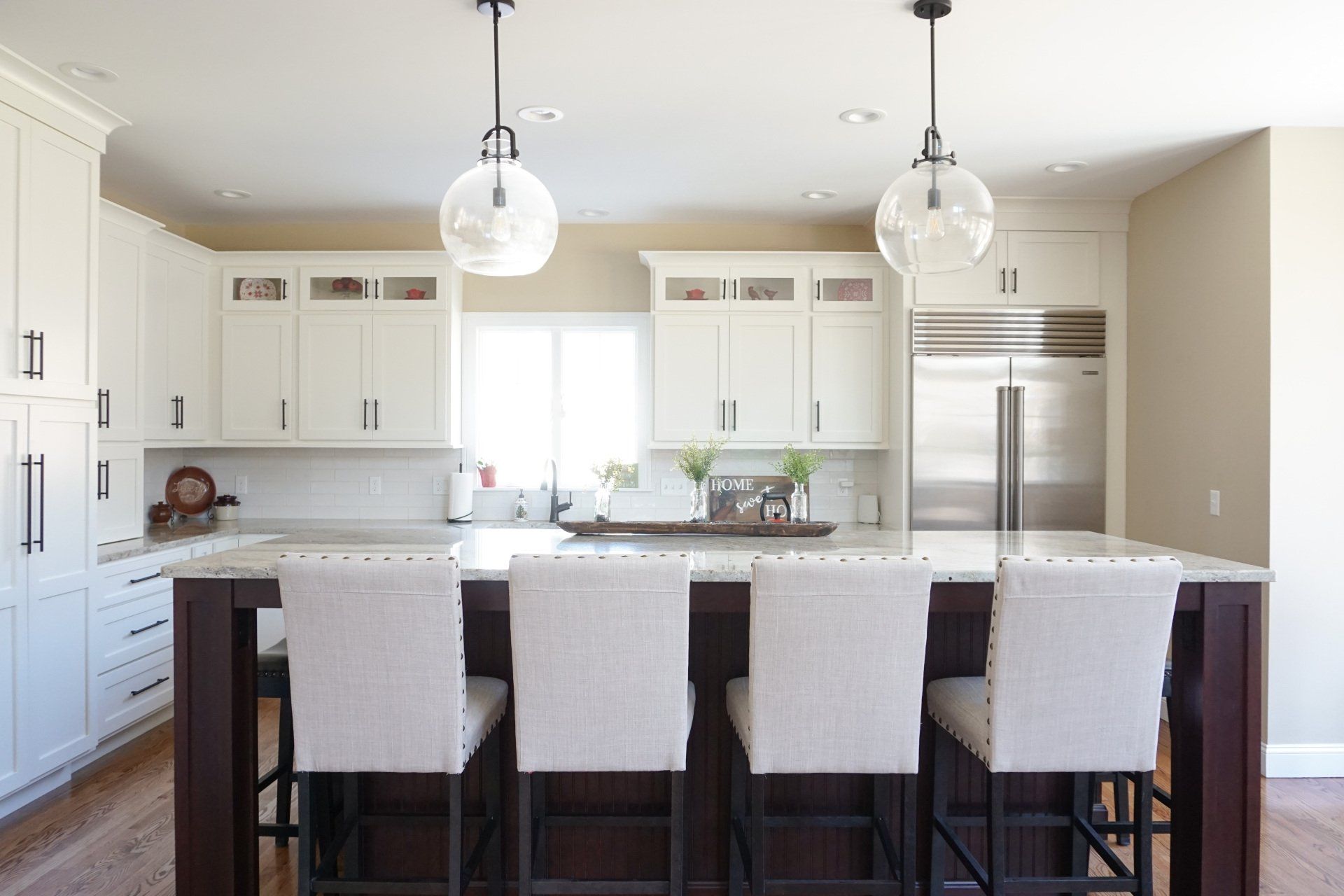 A kitchen with white cabinets , stainless steel appliances , and a large island.