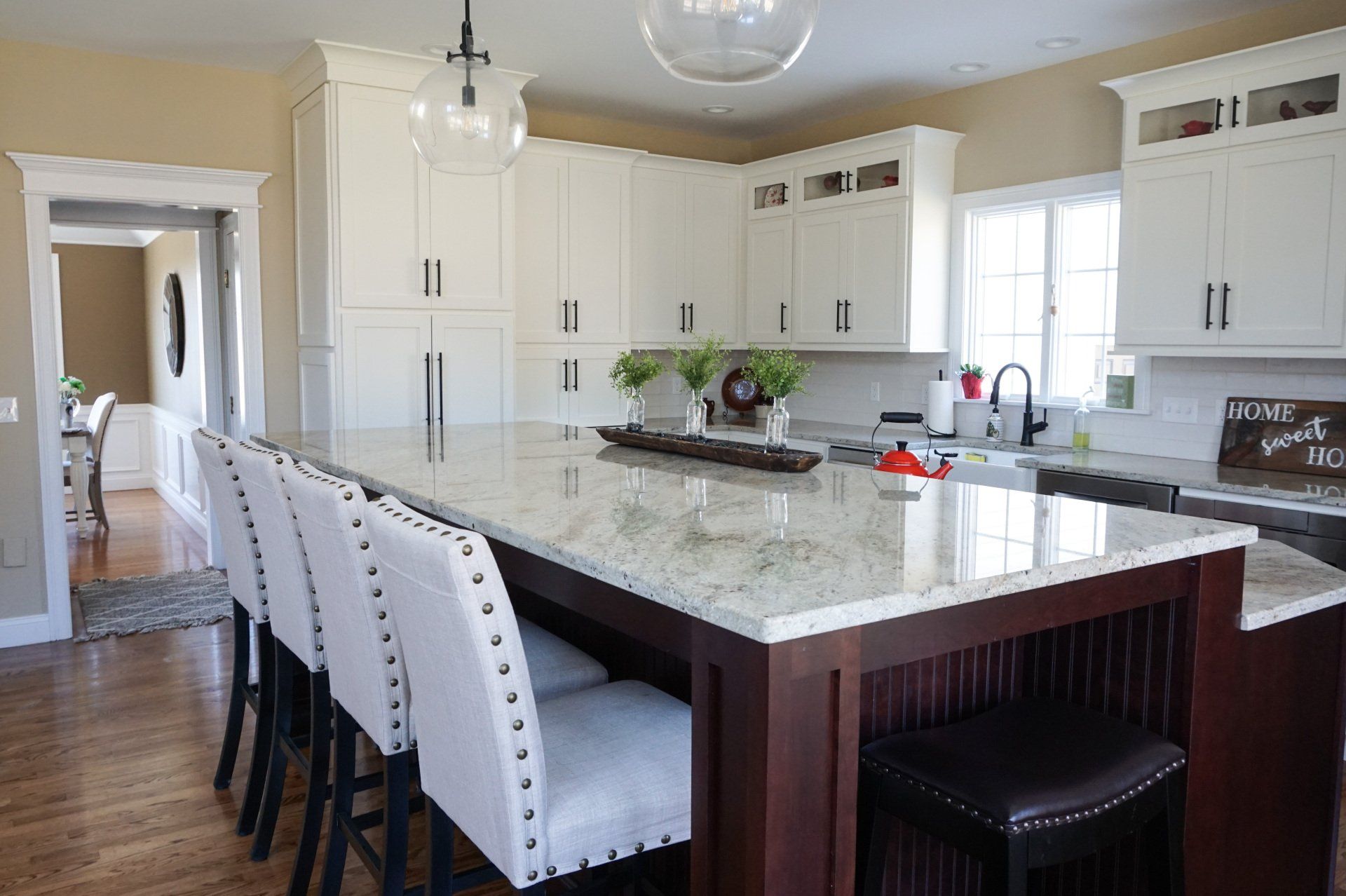 a kitchen with white cabinets and a sign that says home sweet home