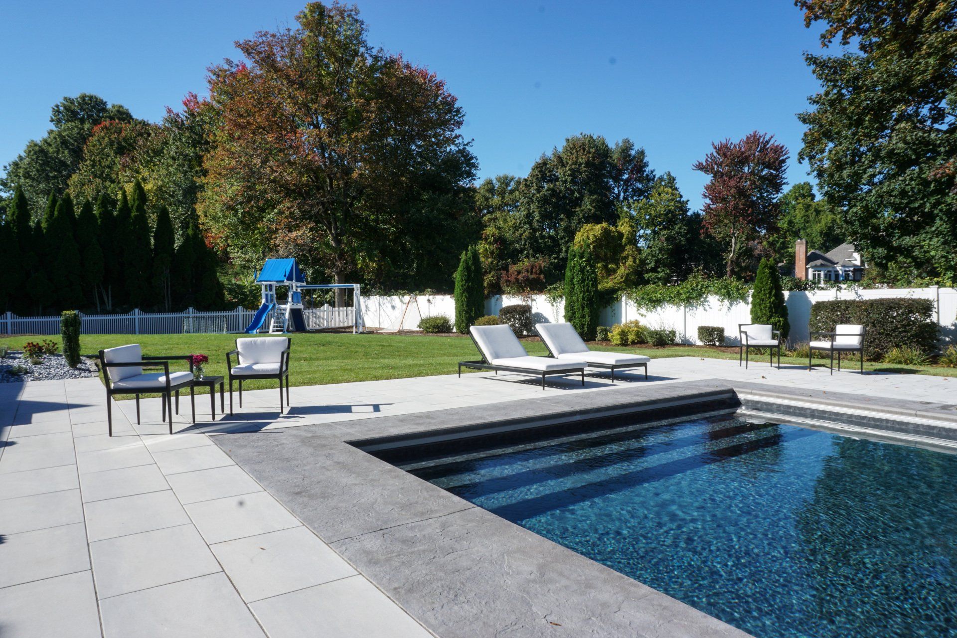 A large swimming pool with chairs and tables around it