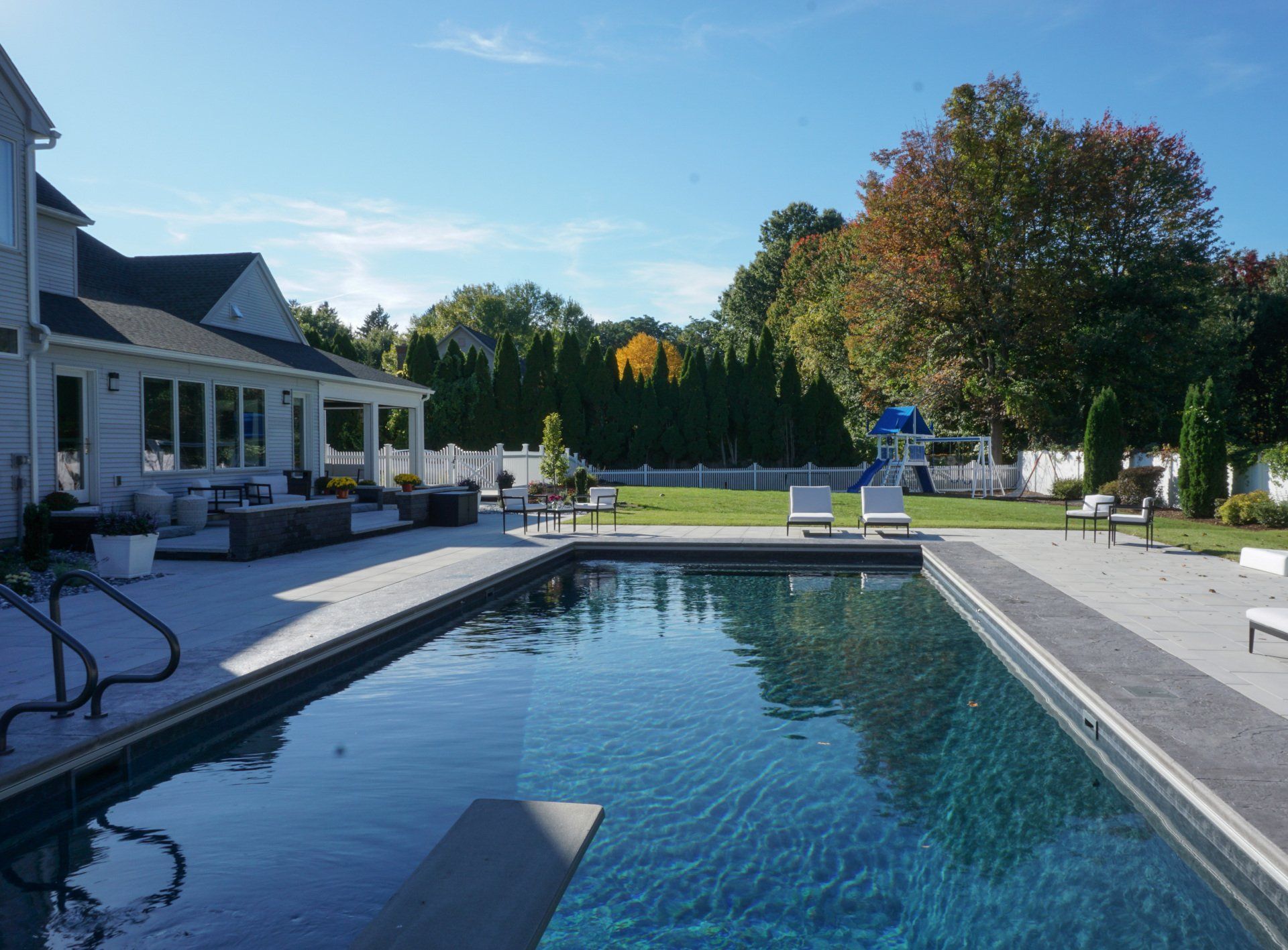 There is a large swimming pool in the backyard of a house.