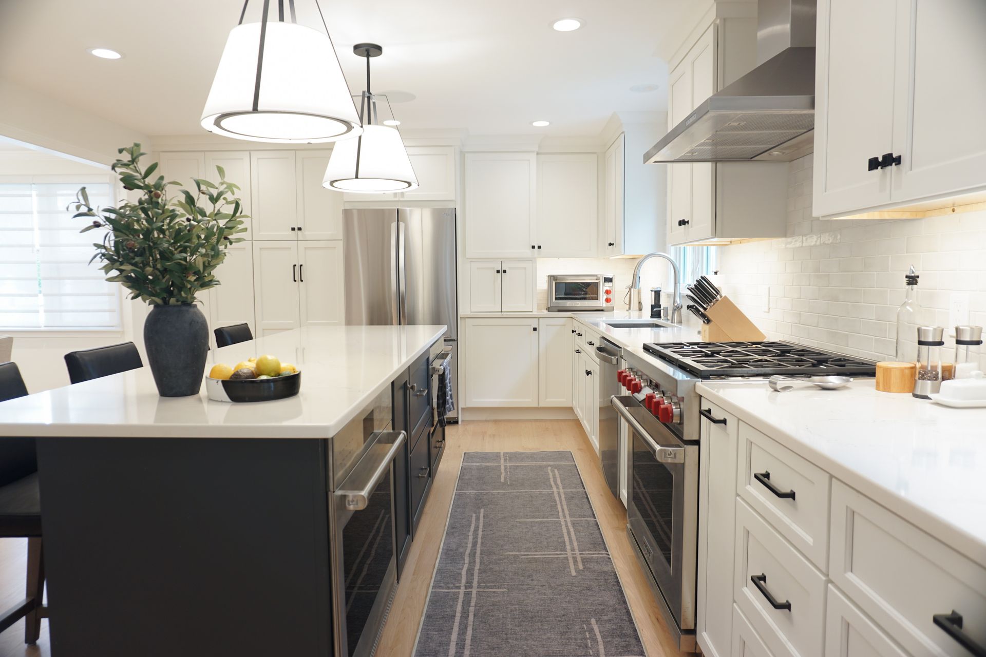 Bright modern kitchen with white cabinets, island, stainless appliances, and pendant lights