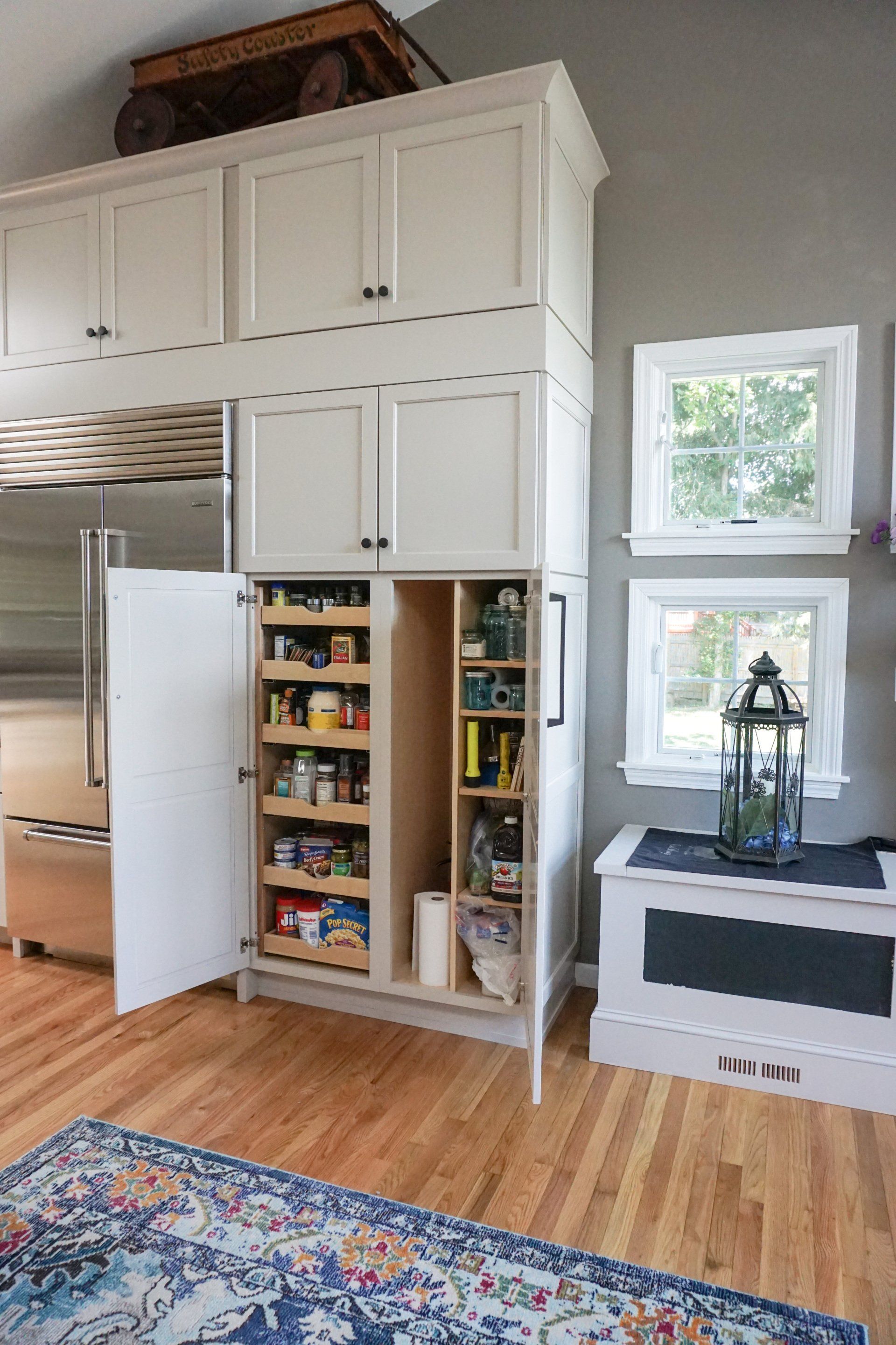 a kitchen with white cabinets and a pantry with the door open. Kitchens by Chapdelaine 