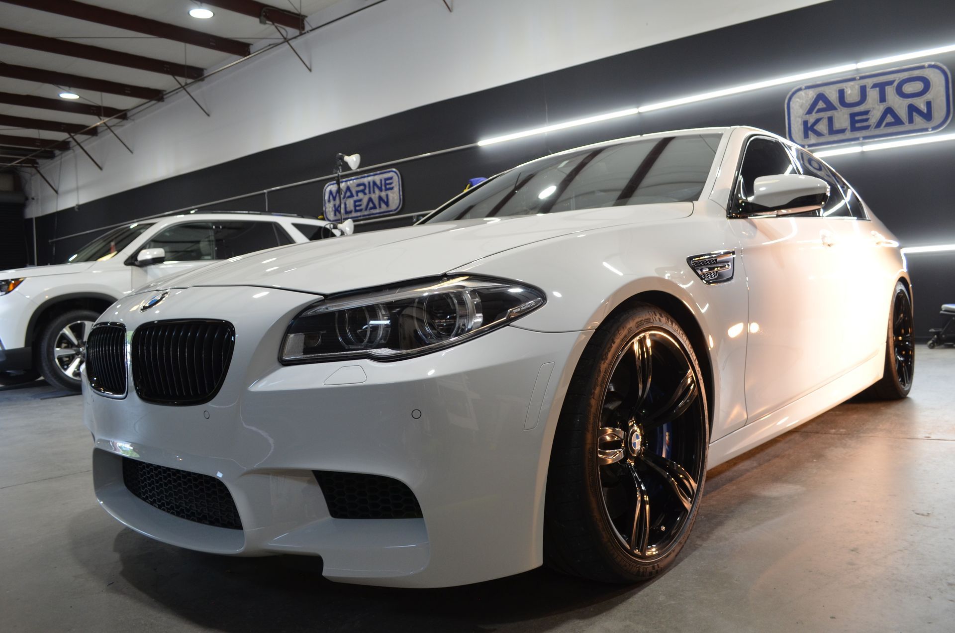 A white bmw m5 is parked in a garage.