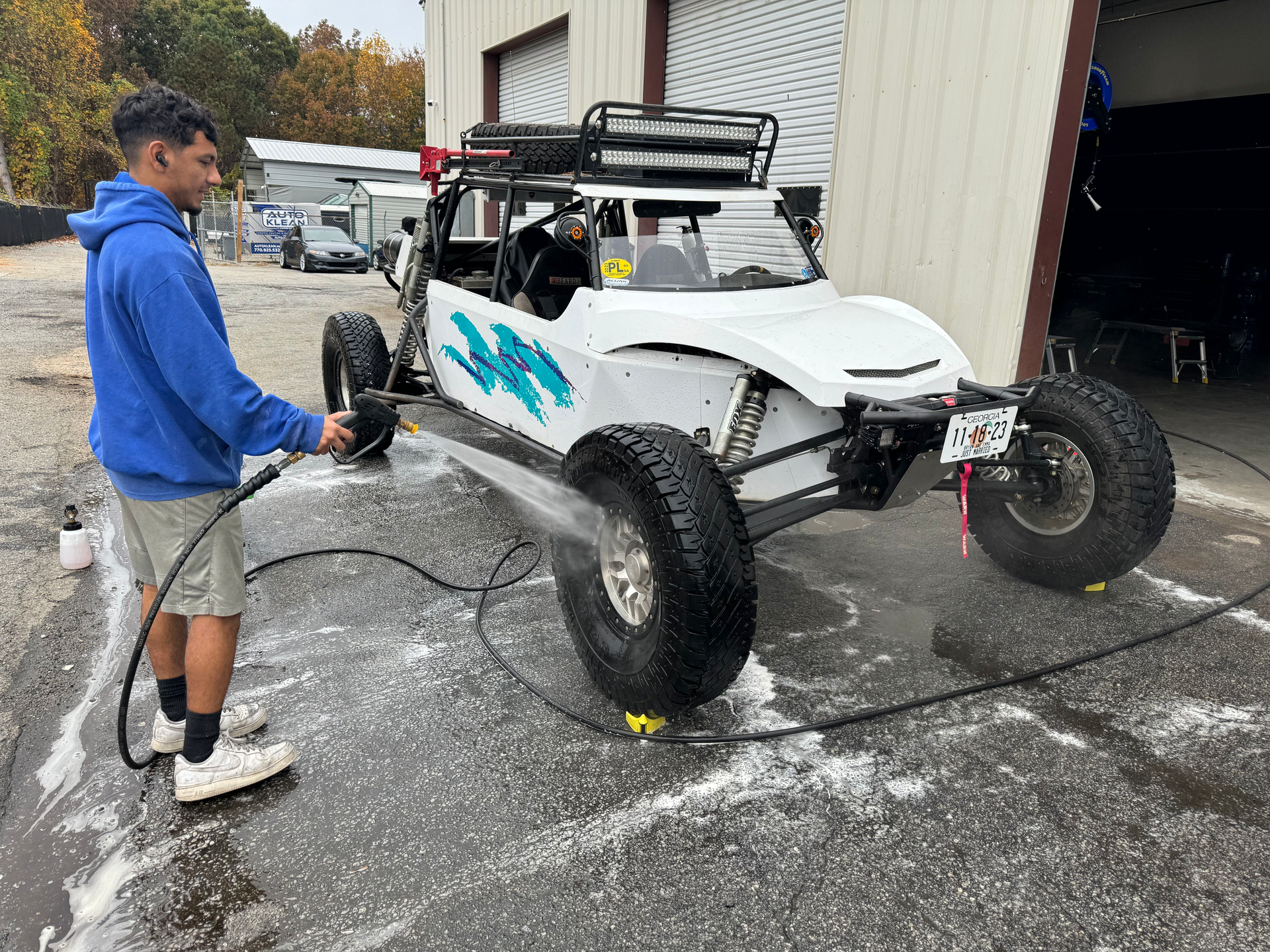 A man is washing a white buggy with a hose.