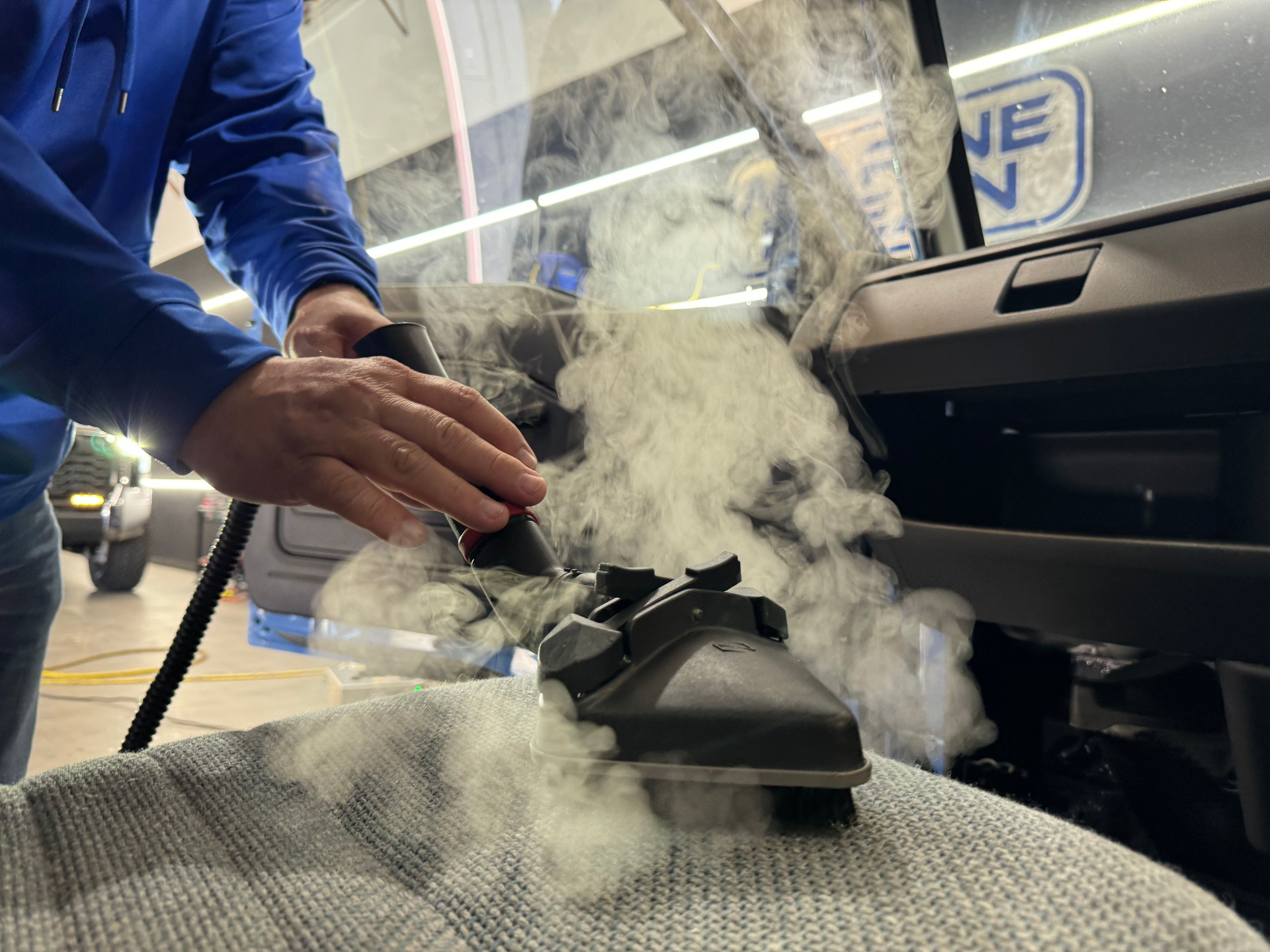 A man is using a vacuum cleaner to clean the interior of a car.