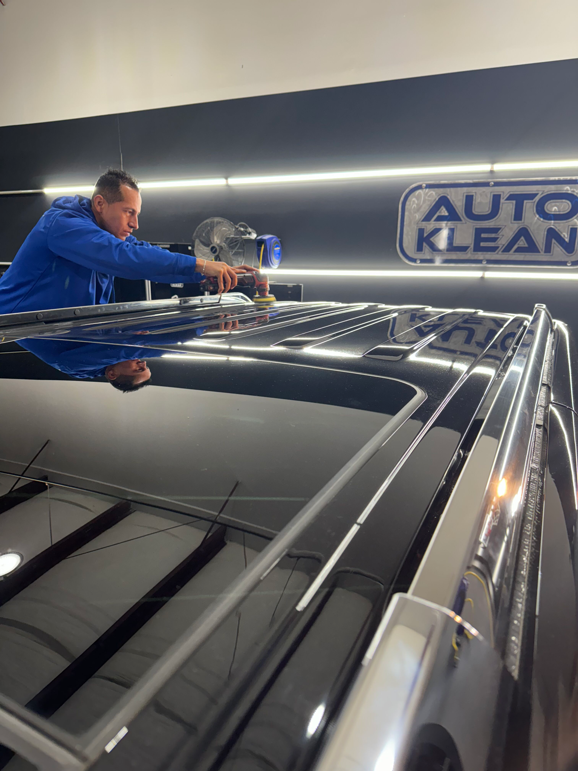 A man is working on the roof of a car in a car wash.