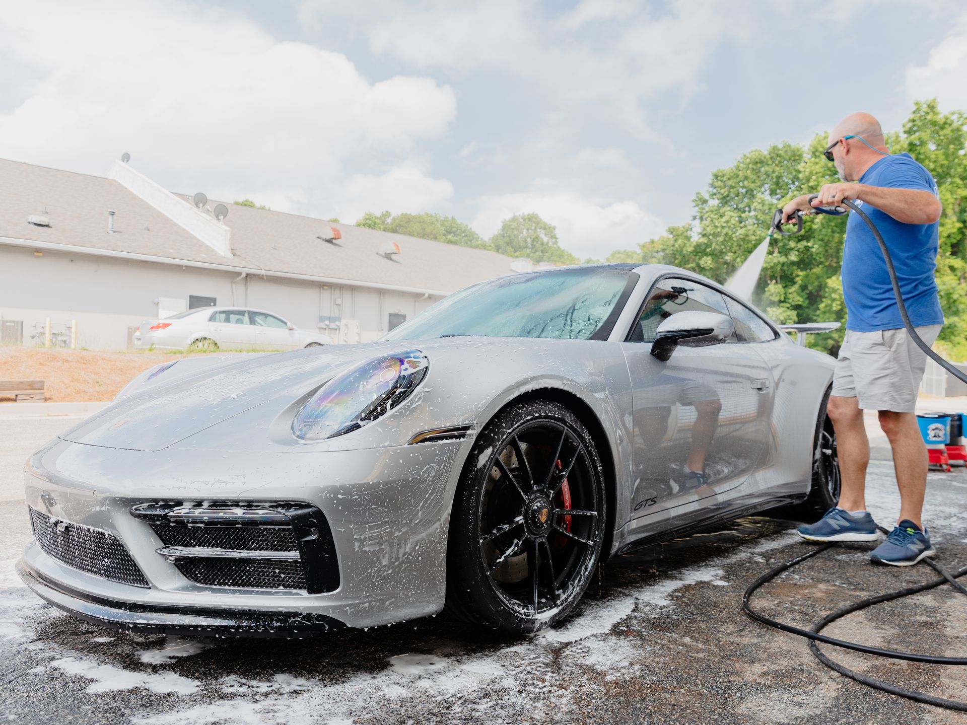 A man is polishing a white car in a garage.