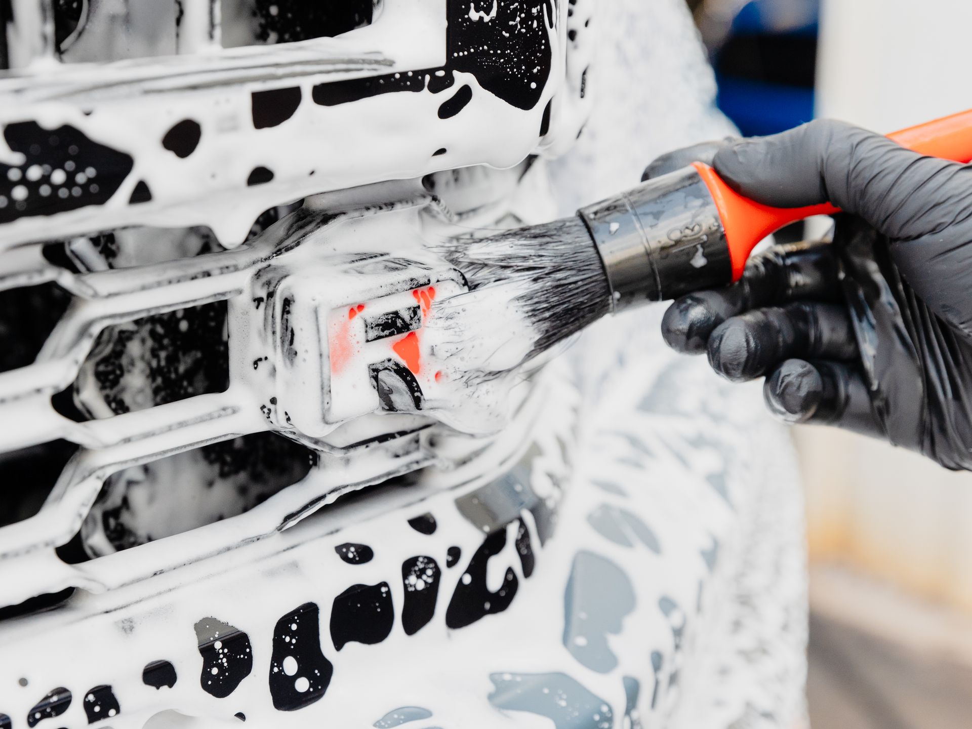 A person is polishing the hood of a car with a machine.