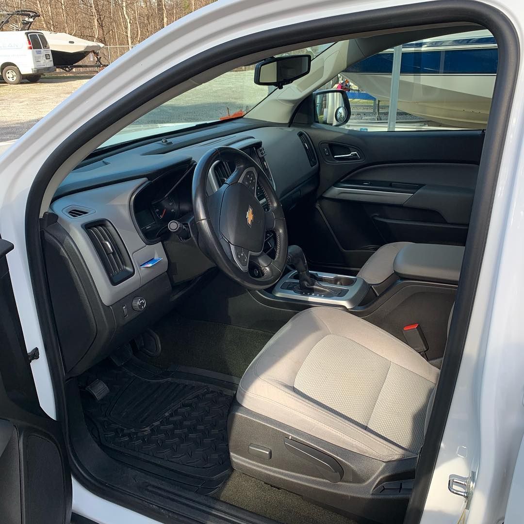 Open driver’s door showing a black car interior with beige seat and steering wheel.