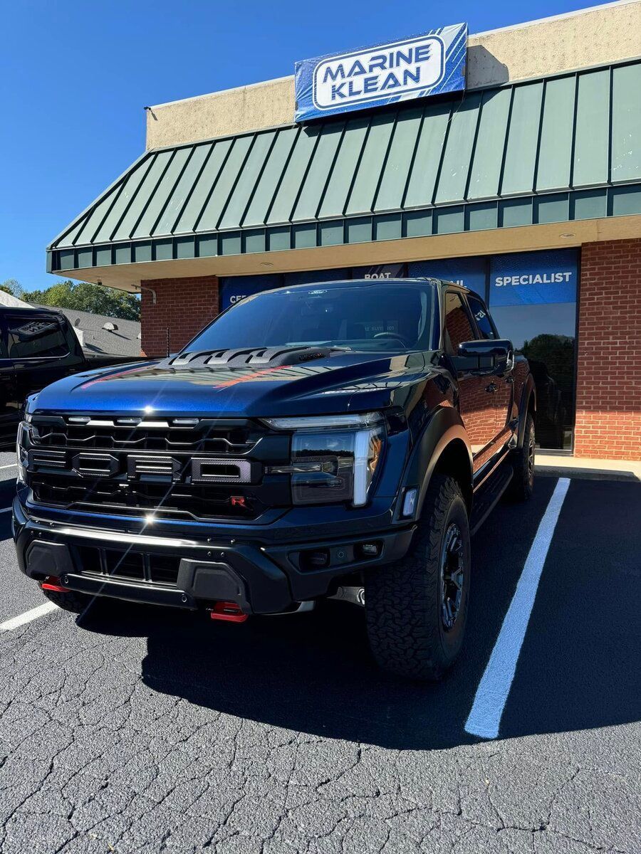Blue Ford Raptor truck parked in front of a Marine Klean storefront.