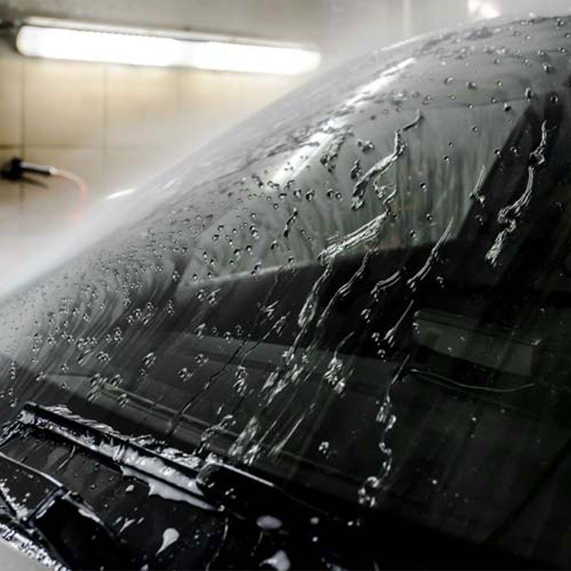 A close up of a car windshield with water drops on it.