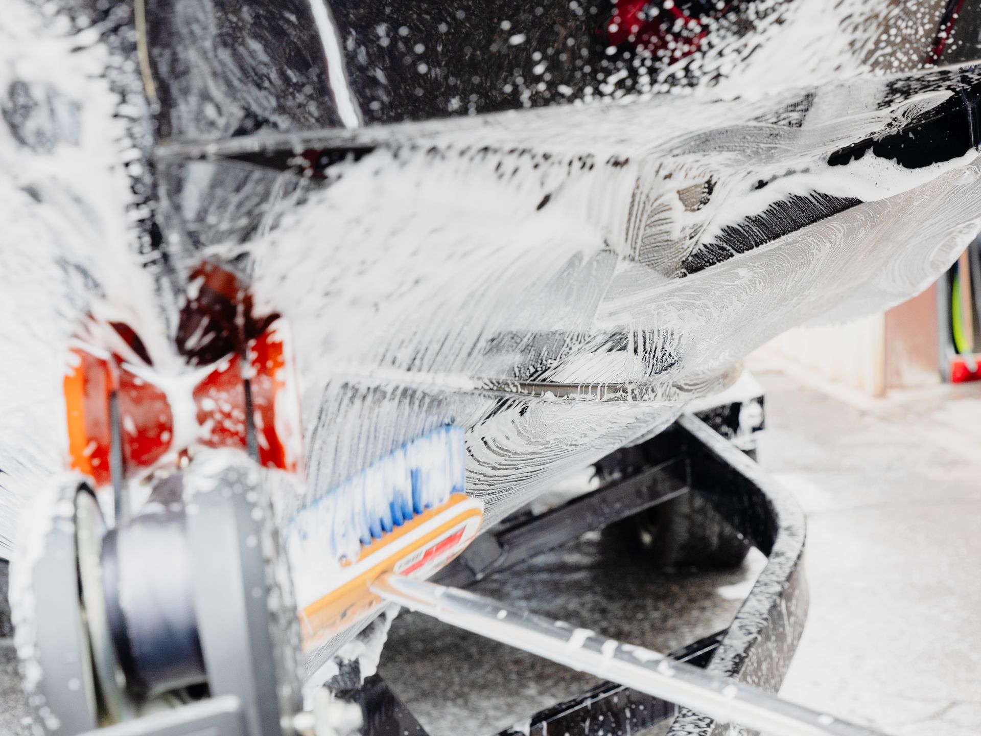 A close up of a car being washed with foam.