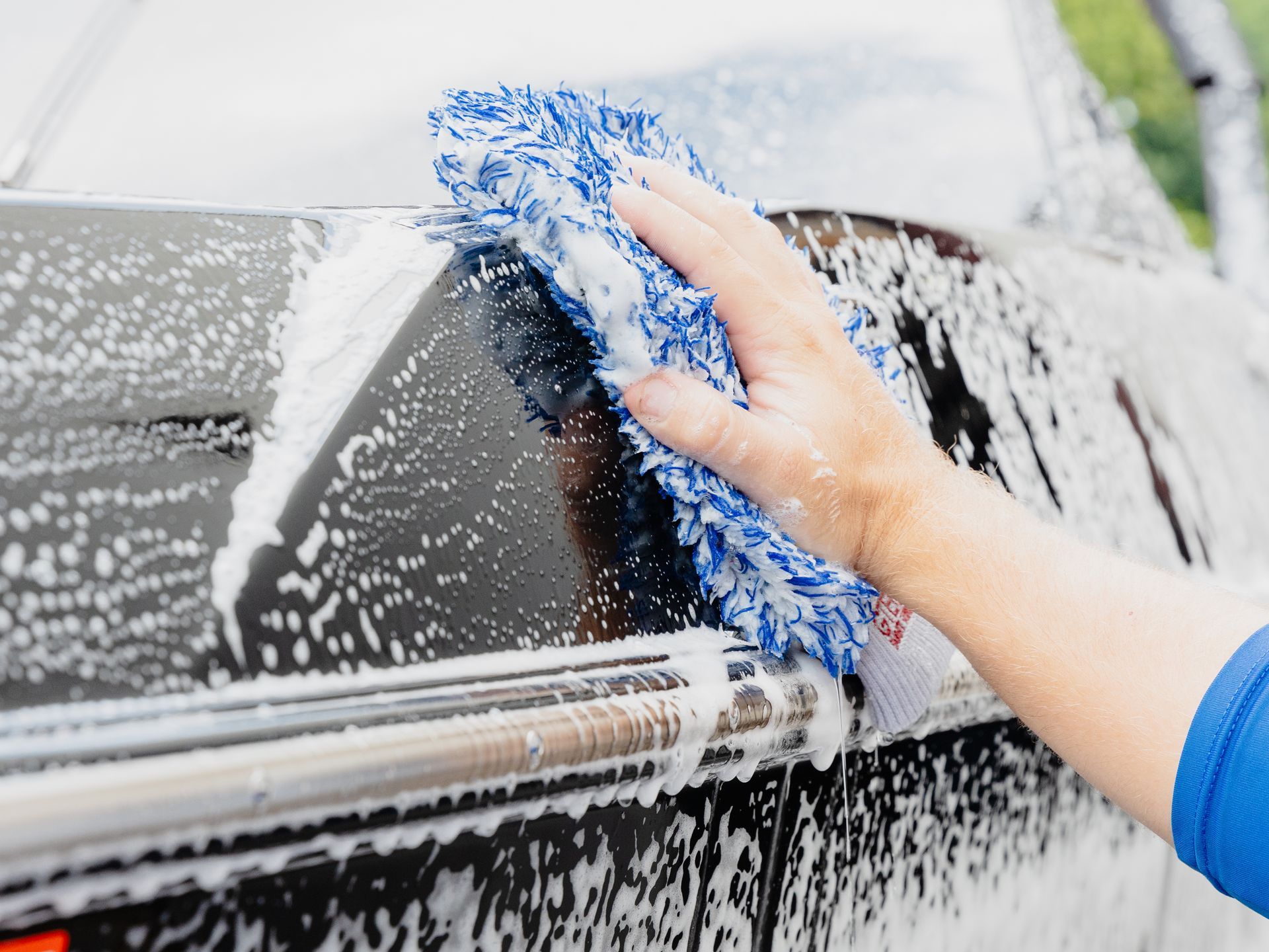 A man is cleaning the steering wheel of a car with a brush.
