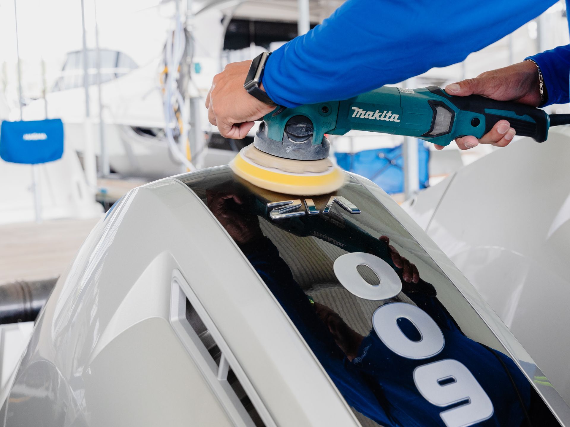 A man is polishing a boat with a makita tool