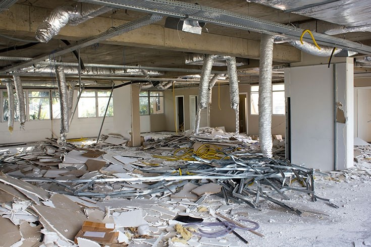 Interior wall with blue and white paint, partially demolished, exposing wood frame and electrical wiring.