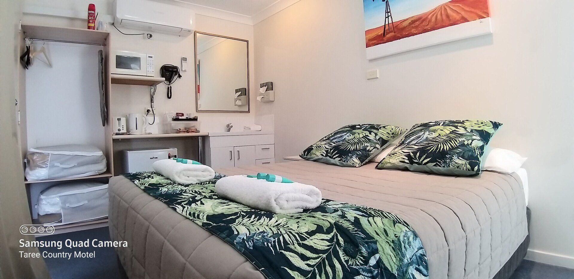 A hotel room with a king size bed and a picture on the wall.