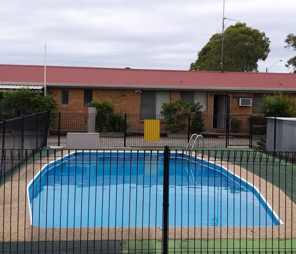 A large swimming pool behind a fence in front of a house