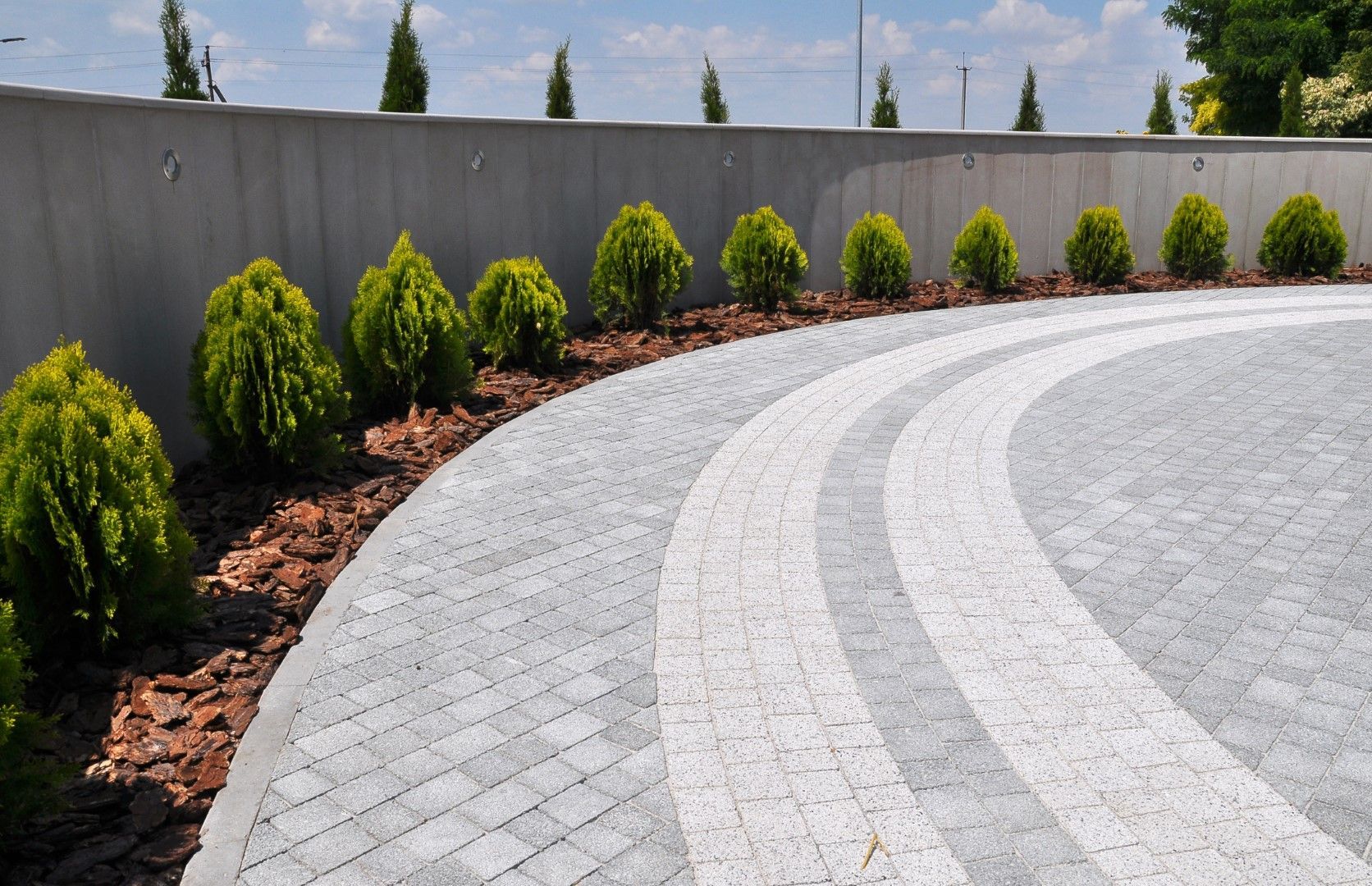 A circular driveway with a concrete wall in the background