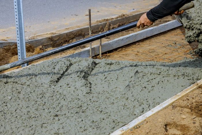 A person is pouring concrete on a sidewalk.