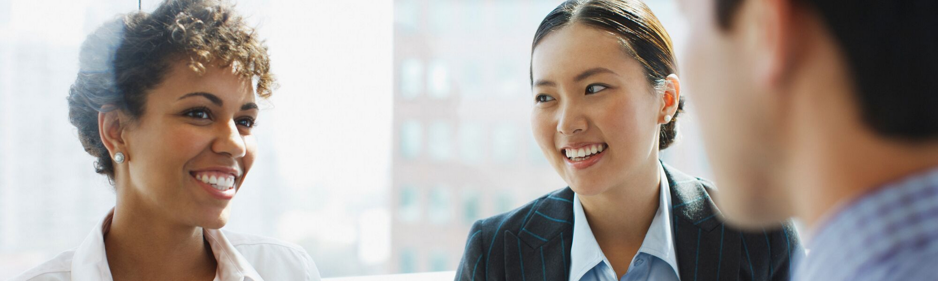 Two colleagues smiling during a business meeting in a bright office
