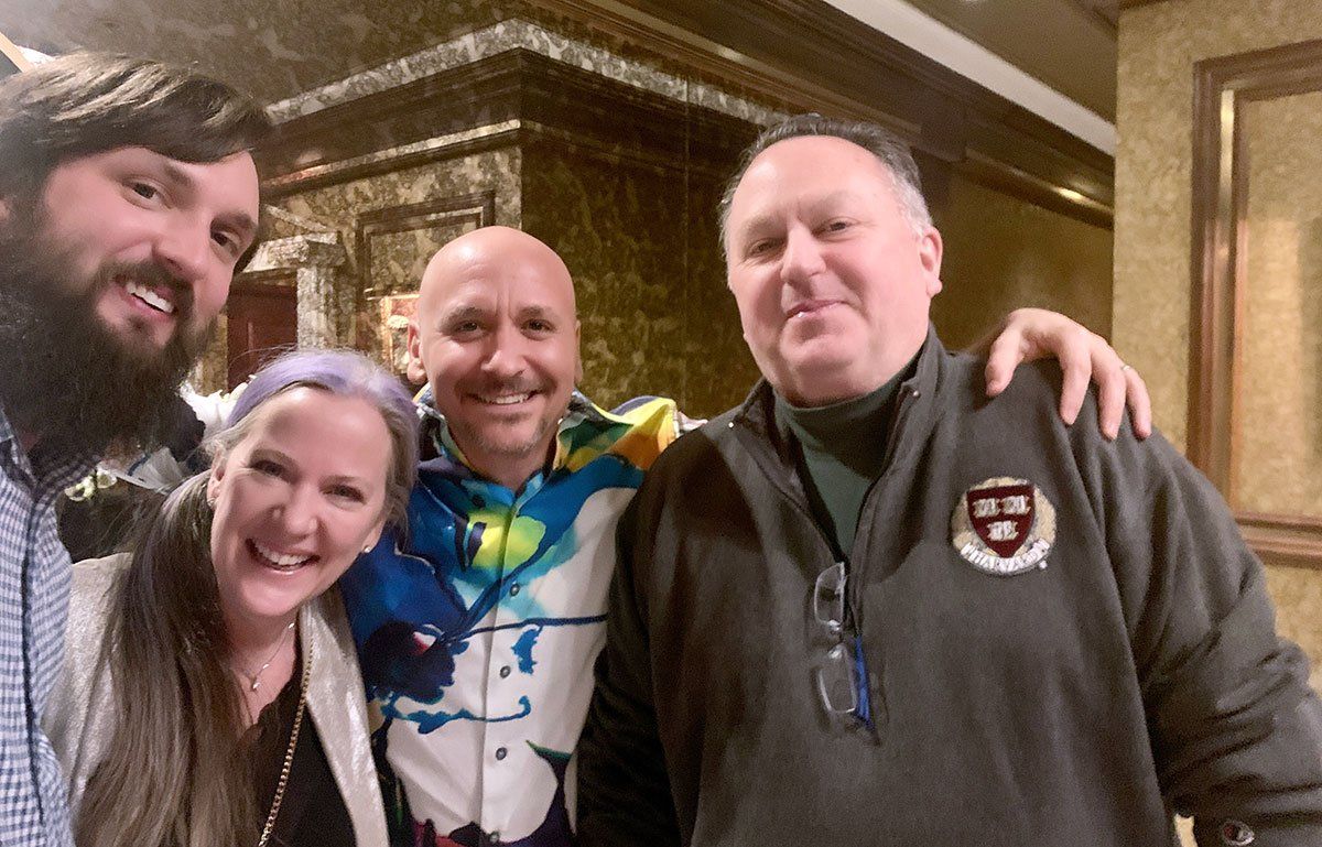 Three men and a woman are posing for a picture together
