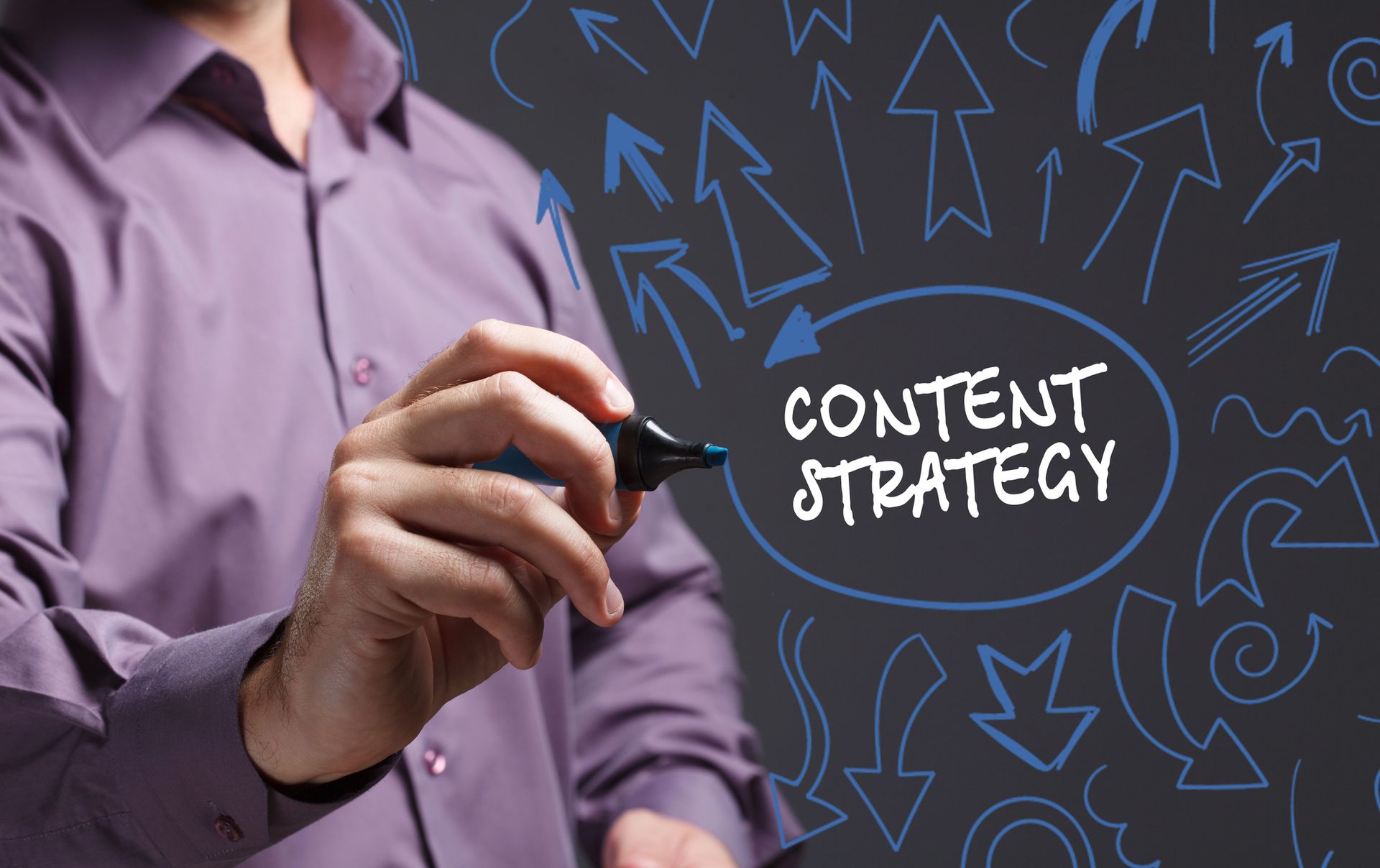 Person writing on a chalkboard with “Content Strategy” and arrows around it
