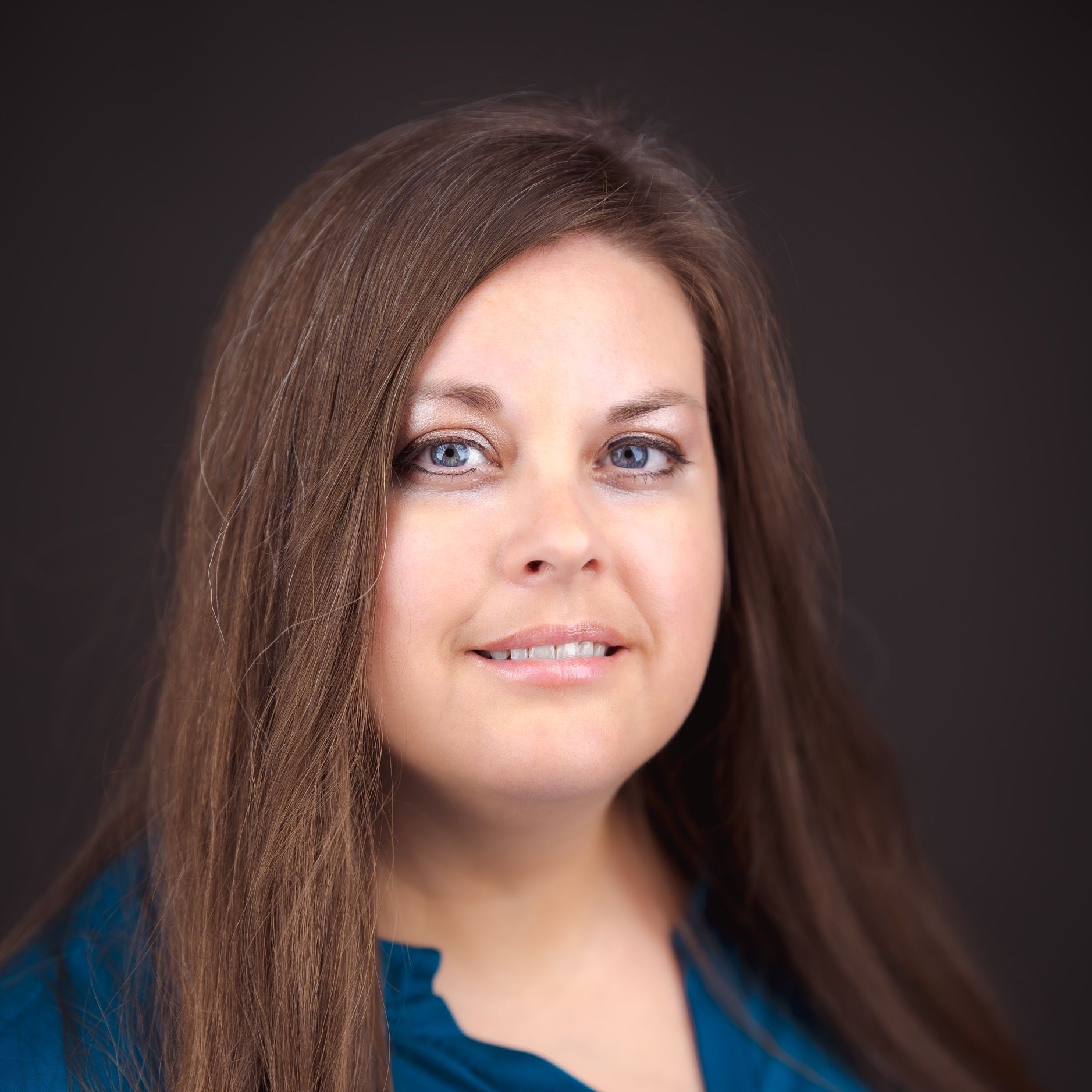 A woman with brown hair and blue eyes is smiling for the camera.