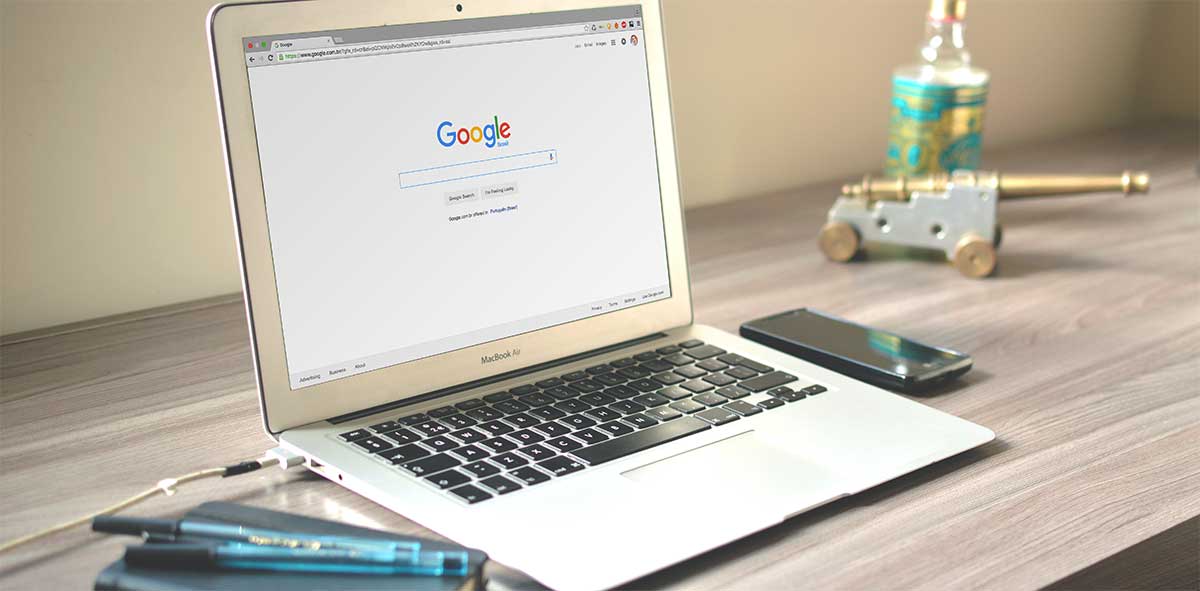 A laptop computer is open to a google page on a wooden desk.