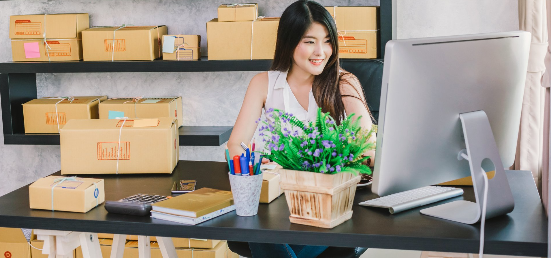 A woman is sitting at a desk in front of a computer.