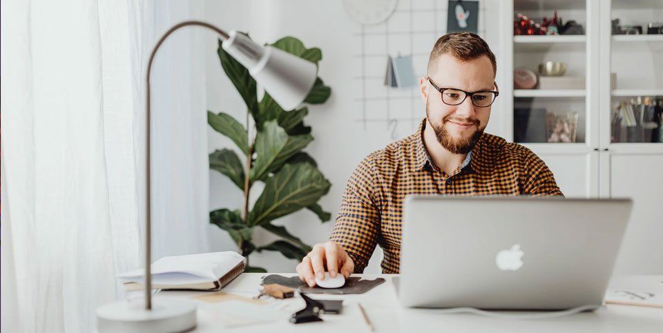 A man is sitting at a desk using a laptop computer.