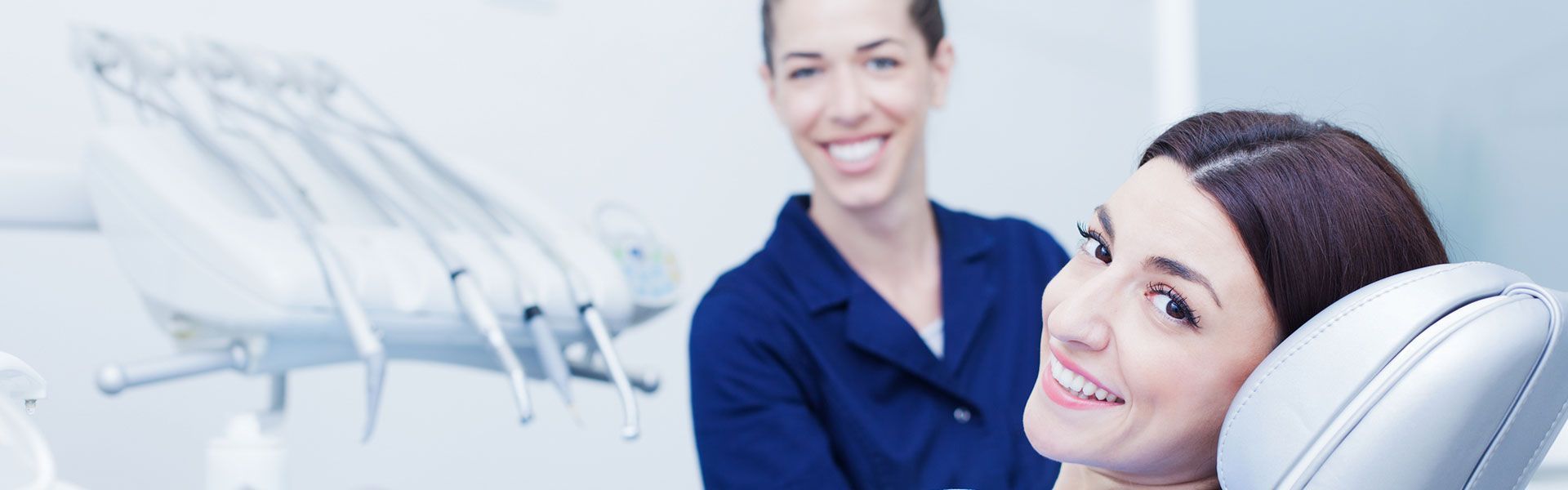 a woman is smiling while sitting in a dental chair