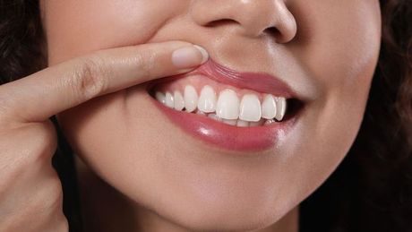a woman is showing her gums with her finger .