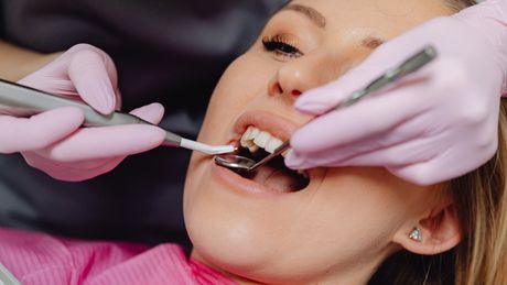 a woman is getting her teeth examined by a dentist