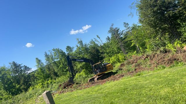 A car is driving down a dirt road next to a pile of dirt.