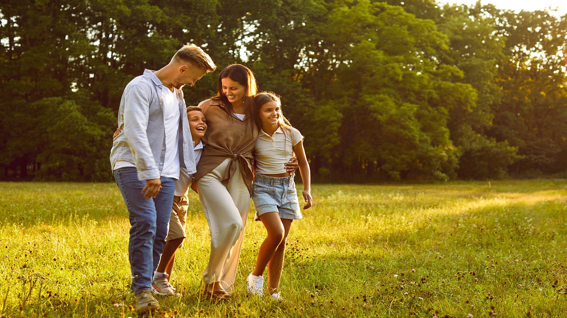 A family is walking through a grassy field.