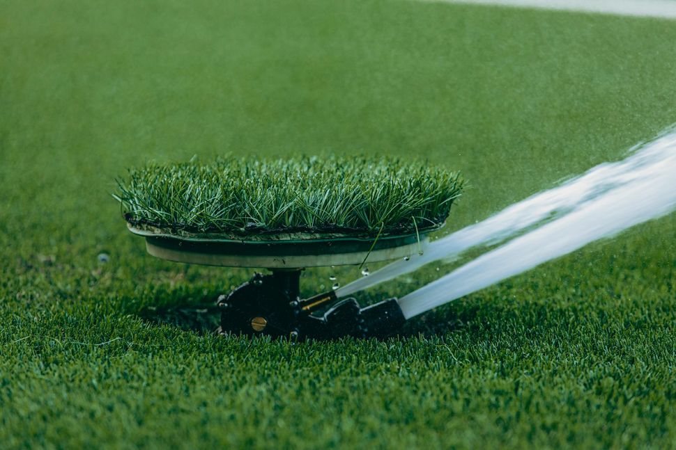 Lawn sprinkler spraying water onto a green grass lawn at close range