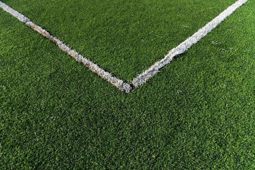 Close-up of a soccer field corner with white boundary lines on green grass