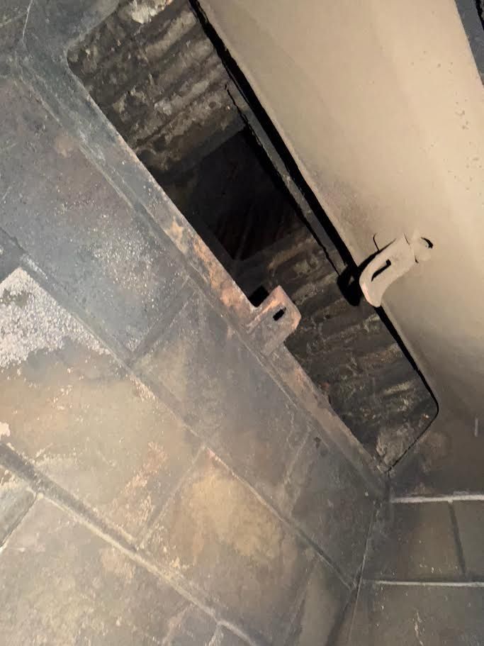 Damaged ceiling with exposed dark opening and wall tiles, viewed at an angle