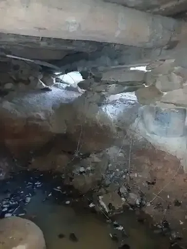 Rocky cave interior with a small pool of water and light entering through an opening