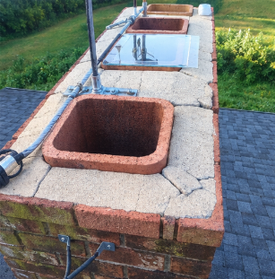 Outdoor stone sink and utility basin on a brick wall with a hose and grassy yard background