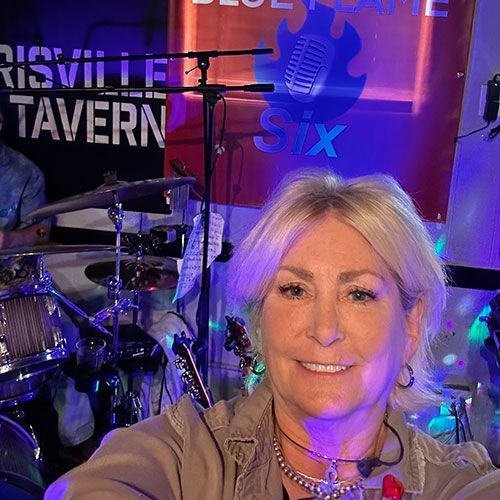 Woman Posing in Front of a Drum Kit on a Purple-lit Stage at Robert A. Lantzy, DMD, LCC in Newtown, PA