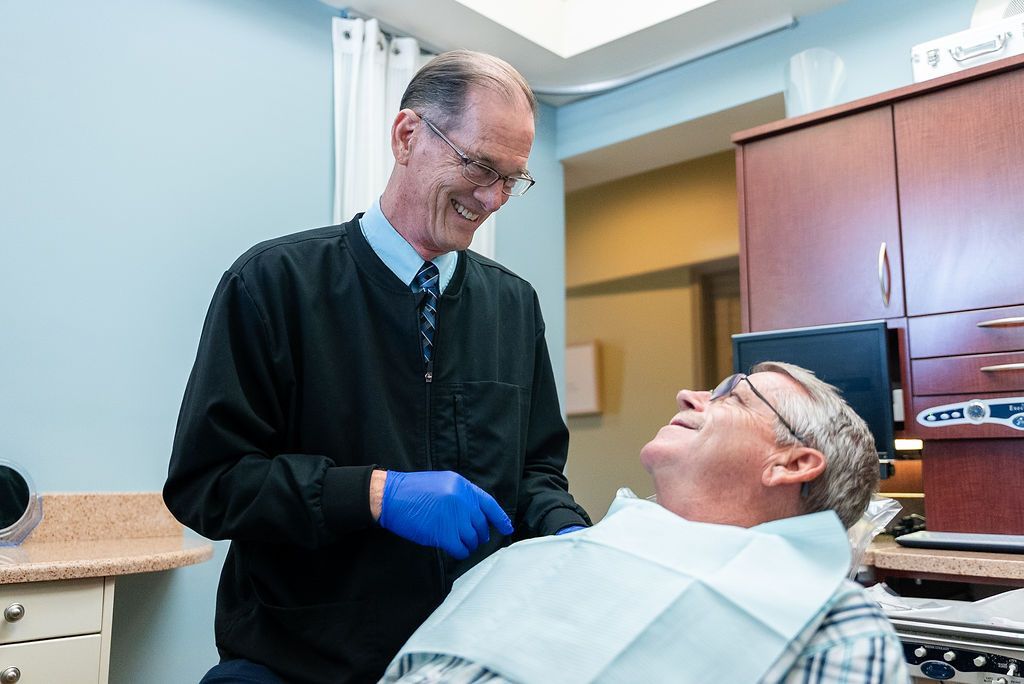 Doctor Bob wearing blue gloves talks to a patient at Robert A. Lantzy DMD, LLC in Newtown, PA