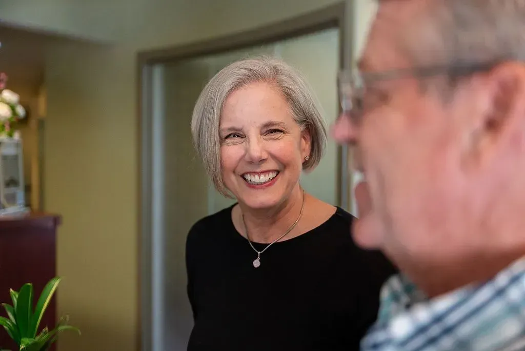 Smiling Marg in black top indoors, with a man at Robert A. Lantzy, DMD, LCC in Newtown, PA