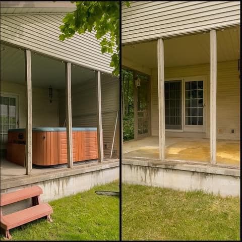 Covered backyard patio with hot tub, concrete steps, and sliding glass doors beside a grassy yard