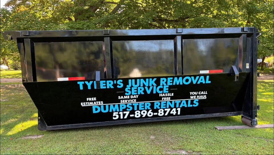 Black dumpster trailer with “Tyler’s Junk Removal Service” and “Dumpster Rentals” on a grassy lawn.