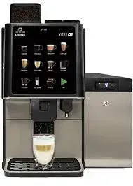 A commercial coffee machine dispensing a layered latte into a glass.