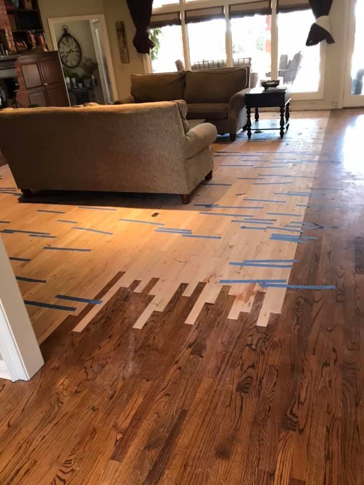 Wooden floor partially stained, with exposed wood sections. Living room setting with furniture visible.