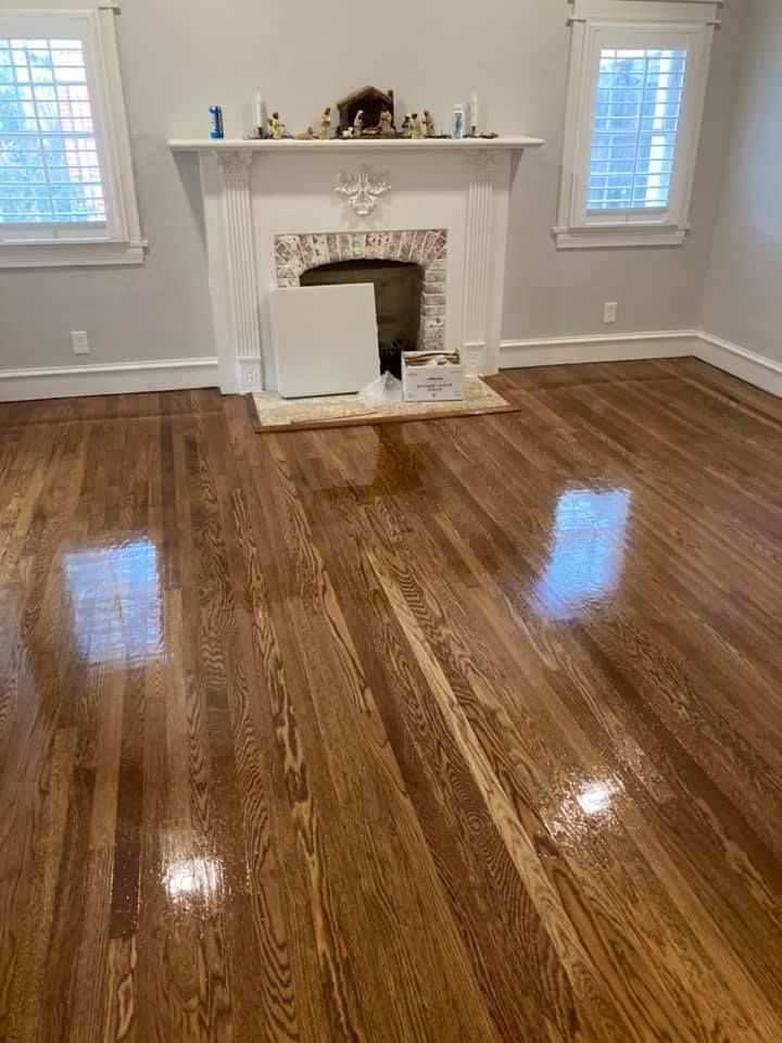 Refinished hardwood floors in a room with a white fireplace, two windows, and light gray walls.