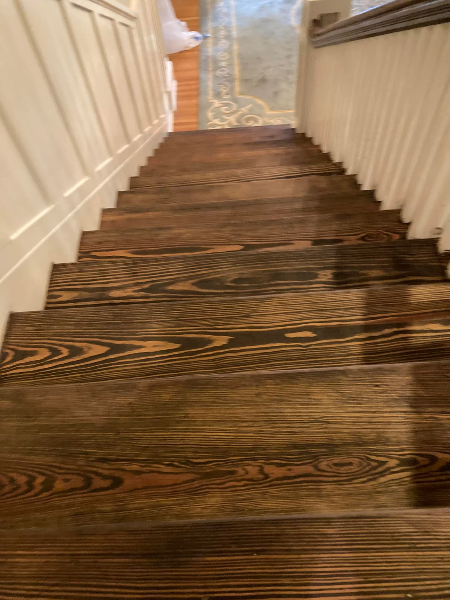 Staircase with wood steps and white walls, viewed from above. The steps are dark brown with a unique grain pattern.