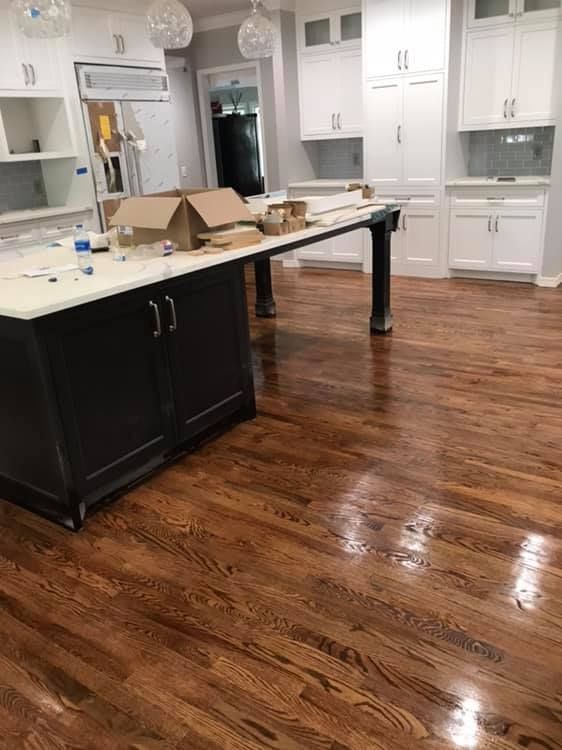 Kitchen with dark brown island, white cabinets, and glossy hardwood floors.